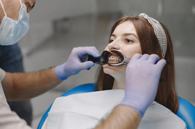 Young woman having braces tightened by orthodontist front view