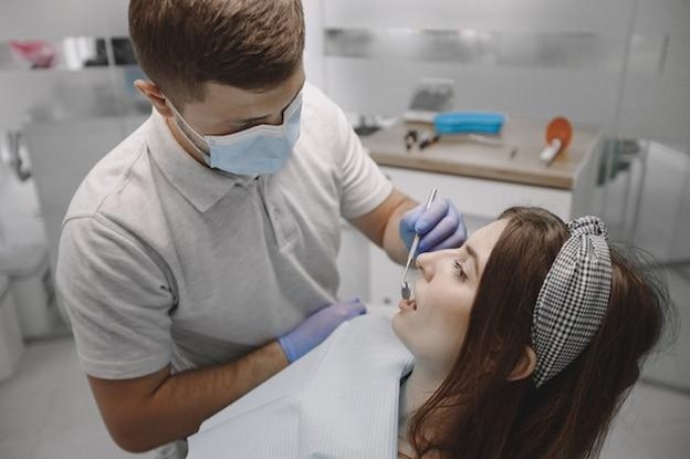 Young woman having braces tightened by orthodontist side view