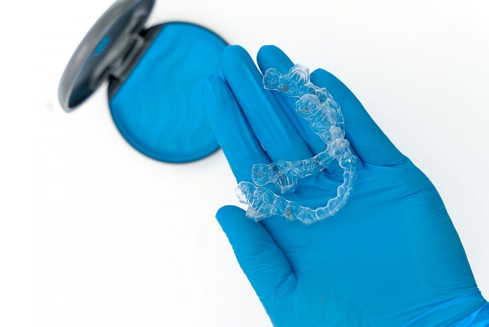 Invisalign clear aligners being held by a gloved hand
